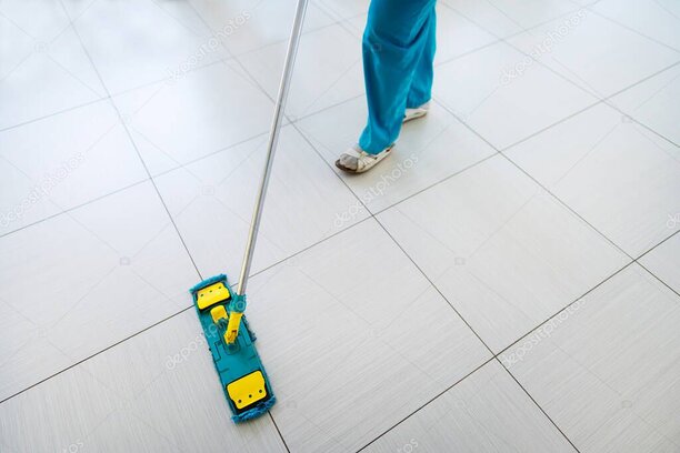 Empleado limpiando el piso de un local comercial con productos de limpieza