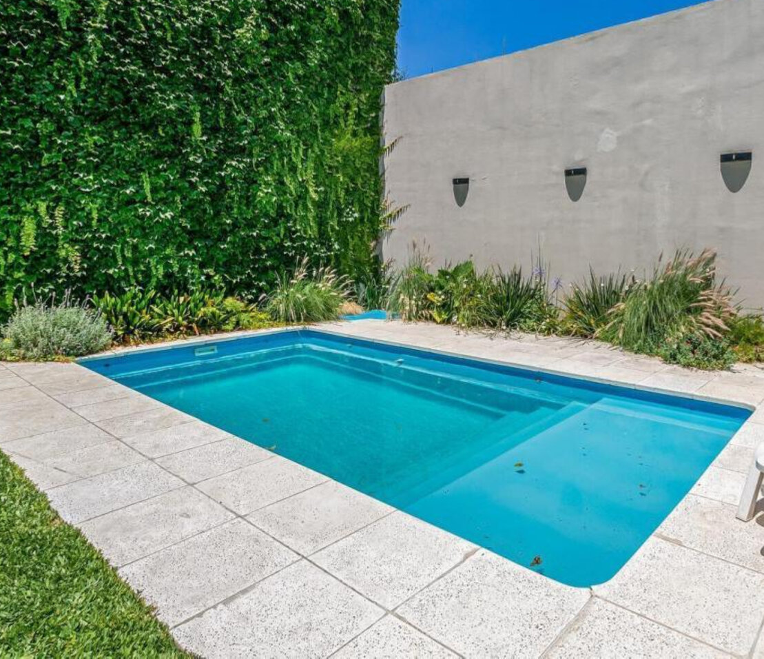 Familia disfrutando de una piscina en el patio de una casa
